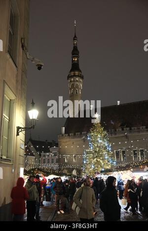 Tallinn, Estonia-29 nov. 2025: folle in un vivace mercato natalizio con un albero di Natale illuminato e la torre del Municipio di Tallinn sullo sfondo Foto Stock