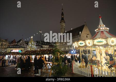 Tallinn, Estonia-29 nov. 2025: Vista notturna del mercato di Natale nella vecchia città di Tallinn, giostra illuminata e bancarelle del mercato con persone Foto Stock