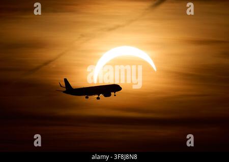 12 agosto 2026, Brandeburgo, Schönefeld: Un Airbus A321 in arrivo da Londra si avvicina all’aeroporto di Berlino-Brandeburgo (BER) durante l’eclissi solare parziale, con il sole parzialmente oscurato dalla luna. Foto: Michael Ukas/dpa Foto Stock