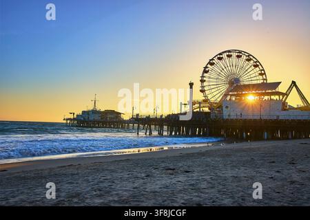 Giostra del pier di Santa Monica al tramonto con spiaggia e oceano in California Foto Stock