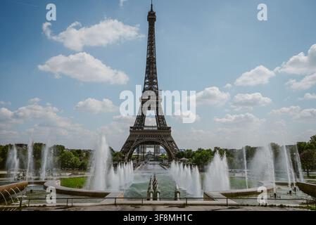 Parigi, Francia - 06 maggio 2022: Vista della Torre Eiffel che si erge sopra le fontane dei giardini del Trocadéro sotto un cielo blu luminoso con nuvole sparse Foto Stock