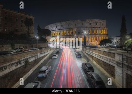 Roma, Italia - 07 novembre 2024: Vista del Colosseo di notte con scie di luce delle auto che passano sulla strada sottostante. Foto Stock