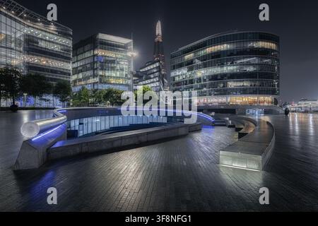 Londra, Regno Unito – 21 settembre 2024: Vista dello Shard che si erge sopra moderni edifici di uffici in vetro e una piazza pubblica elegante e illuminata di notte Foto Stock