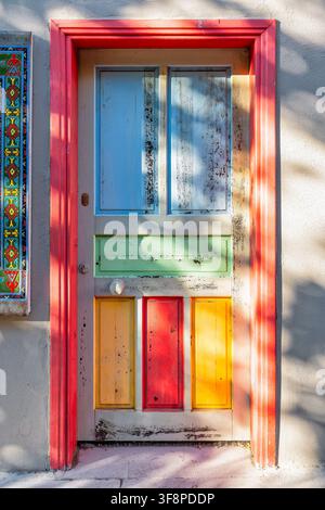 Coloreggiata porta di legno rustica con piastrelle tradizionali nel quartiere storico di Kaleici di Antalya, Turchia, caratterizzata da una vivace cornice rossa e m consumata Foto Stock