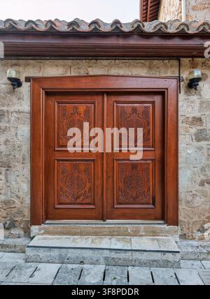 Una porta in legno tradizionale ornata con intagli di melagrane su una vecchia casa in pietra nel quartiere storico di Kaleici ad Antalya, Turchia Foto Stock