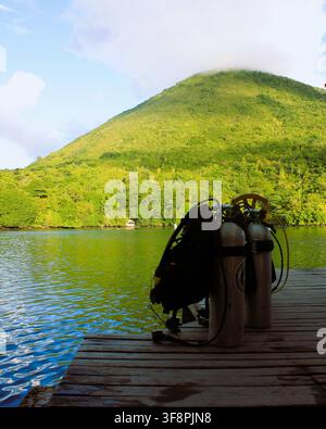 Taniche per immersioni subacquee su un molo di legno al Delfika Homestay con vista scenografica sul vulcano Gunung Api a Banda Neira, Maluku, Indonesia Foto Stock