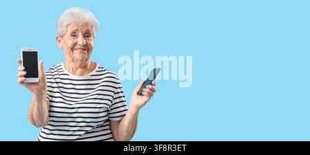 Donna anziana sorridente che tiene due smartphone con schermi vuoti, tecnologia per gli anziani e inclusione digitale Foto Stock