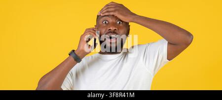 Uomo nero preoccupato che parla al telefono con espressione scioccata, sfondo studio Foto Stock