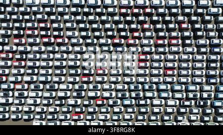Vista aerea dall'alto di auto nuove parcheggiate in un lotto di distribuzione organizzato Foto Stock
