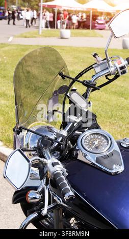 Scatto dettagliato del manubrio e del cruscotto della moto, con tachimetro ed elementi cromati. La composizione verticale evidenzia la lavorazione artigianale del veicolo Foto Stock
