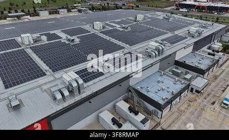 Edificio industriale con una grande serie di pannelli solari sul tetto, che genera energia pulita e sostenibile per le operazioni Foto Stock