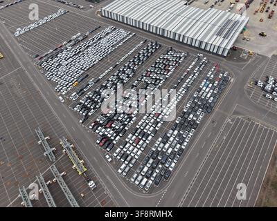 File di auto nuove parcheggiate su un ampio lotto in attesa di trasporto, evidenziando la logistica automobilistica e il commercio internazionale Foto Stock