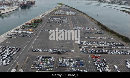Vista ad angolo alto di migliaia di auto nuove e usate parcheggiate in una grande struttura portuale, in attesa di spedizione o distribuzione Foto Stock
