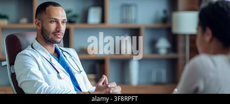Giovane medico maschio concentrato che interagisce con un paziente in un contesto sanitario, concetto di assistenza sanitaria Foto Stock