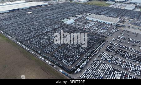 Grande struttura di stoccaggio con migliaia di veicoli nuovi in attesa di spedizione, che mostra la produzione di massa Foto Stock