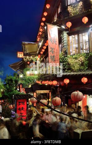 Casa del tè A-MEI di notte a Jiufen, Taiwan, con lanterne rosse e persone sfocate in movimento Foto Stock