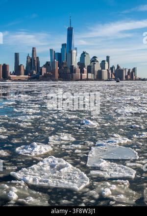 Città bassa di Lower Manhattan con grattacieli del World Trade Center visti attraverso il fiume Hudson ghiacciato coperto di banchi di ghiaccio durante l'inverno, New York City Foto Stock