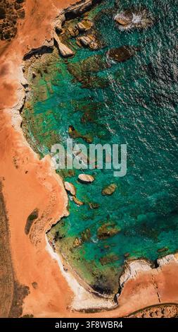 Vista aerea dall'alto della costa rocciosa frastagliata e dell'acqua cristallina del mare. Foto Stock