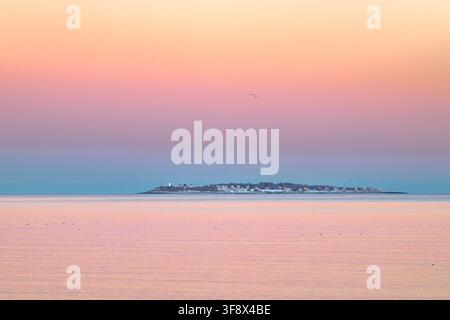 Tramonto rosa sull'isola di Bakers nel Salem Sound che si riflette nel mare Foto Stock