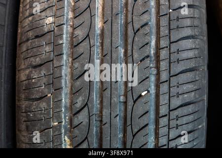 Vista ravvicinata dettagliata del battistrada di uno pneumatico di auto consumato. Si vedono scanalature e canali intricati progettati per la presa, che mostrano usura e sporcizia. Foto Stock