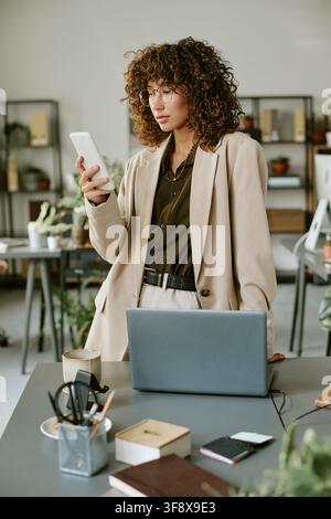 Donna d'affari che lavora su laptop e smartphone in ufficio Foto Stock