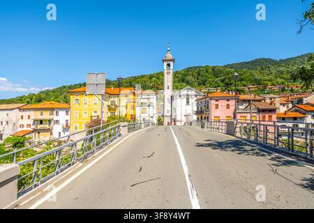Una vista pittoresca del ponte del canale che attraversa il fiume Soca in Slovenia. Edifici colorati costeggiano la strada, offrendo un'atmosfera incantevole contro un cielo blu terso. Foto Stock