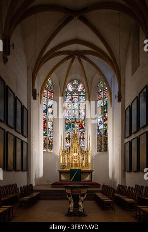 Lipsia, Germania - 12 lug 25: Interno gotico della Chiesa di San Tommaso a Lipsia, che mostra l'altare, le vetrate colorate, il soffitto a volta e le file di w Foto Stock