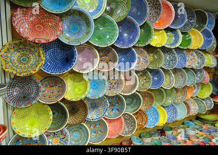 Una esposizione murale di piatti e ciotole in ceramica tunisina dipinti a mano e colorati in un negozio, Tunisia Foto Stock