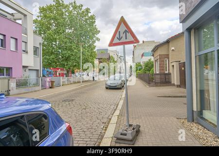 Il cartello stradale con due frecce nere che puntano in direzioni opposte è il segnale di pericolo 125 traffico in arrivo. Ha una forma triangolare con sfondo bianco Foto Stock
