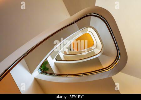 Vista dell'elegante scala a chiocciola al The Peninsula Tokyo, con ringhiere lisce e curve e una calda luce dorata che si riflette dal centro a Ch Foto Stock