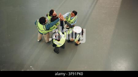 Ingeniero, squadra e high five nel cantiere per collaborazione, gestione del progetto e supporto. Sopra, gruppo di costruzione o persone nello spazio per Foto Stock