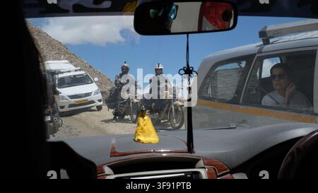 Una vista dell'ingorgo stradale su un'autostrada di montagna con motociclisti e auto visti attraverso il parabrezza di un'auto nel Ladakh, India. Foto Stock