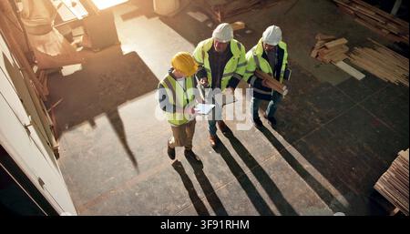Camminata, uomini e falegnami in officina con tablet sulla produzione di mobili in collaborazione. Tecnologia digitale, conversazione e lavoratori del legno con Foto Stock