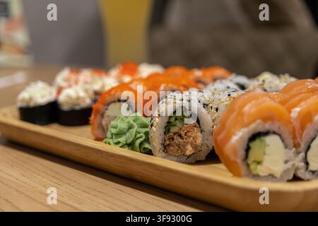 Deliziosa varietà di rotoli di sushi freschi serviti su una tavola di legno, con salmone e formaggio cremoso, offrendo un'estetica elegante per una fo professionale Foto Stock