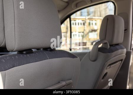 Rivestimenti grigi strutturati coprono i sedili all'interno di un'automobile passeggeri, dove un pratico vassoio pieghevole si trova dietro il poggiatesta per evidenziare la comodità Foto Stock