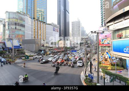 Una vista ad angolo alto di un incrocio affollato del centro città di Bangkok con traffico intenso e alti edifici moderni Foto Stock