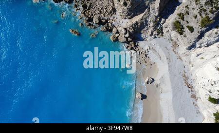 Splendida veduta aerea di acqua turchese cristallina che incontra una costa di calcare frastagliata con una spiaggia sabbiosa isolata. Foto Stock