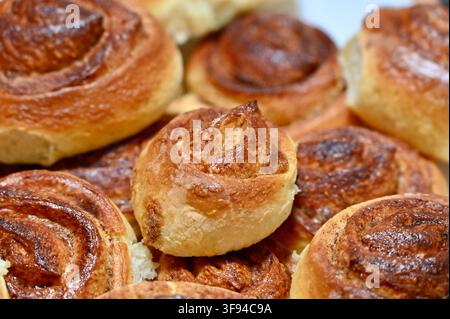 Fotografia ravvicinata commerciale di una deliziosa pila appetitosa di panini alla cannella dorati e appena sfornati impilati insieme, che mostra le loro ricche texture a spirale e le croste croccanti. Foto Stock