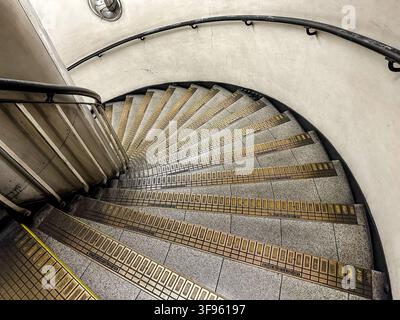 Vista aerea di una scala a chiocciola con curve strette e ringhiere metalliche in una stazione della metropolitana del centro di Londra Foto Stock