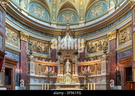 Pannelli di bronzo a rilievo che raffigurano scene religiose storiche affiancano la statua dell'altare principale coperta da un baldacchino di Santo Stefano al centro dell'abside del santuario Foto Stock
