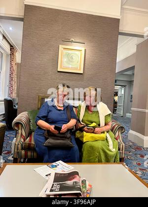 Due anziane signore con telefoni cellulari al The White Lion Hotel, Aldeburgh Suffolk P15 5BJ Regno Unito Foto Stock