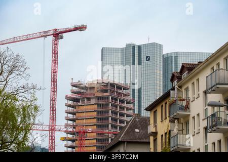 Una gru torre rossa domina il lato sinistro dell'inquadratura, svettando su un edificio in costruzione, con la distintiva facciata in vetro della Deutsche Foto Stock