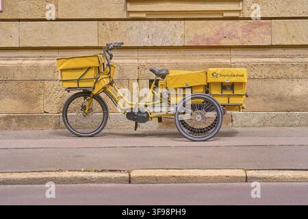 Consegnare lettere in bicicletta e partire come postino, bicicletta postale gialla parcheggiata sul lato della strada davanti a una facciata storica, Magdeb Foto Stock