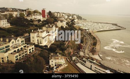 Vista aerea di una costa con un porticciolo, edifici su scogliere e una strada lungo la riva, Torquay, Devon, Regno Unito Foto Stock