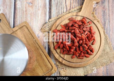 Bacche di goji essiccate su un vassoio di legno in una cucina Foto Stock