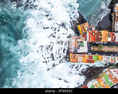 Foto aerea vista dall'alto di onde selvagge nell'Oceano Atlantico con case colorate sull'isola di Tenerife a Puerto de la Cruz, Spagna Foto Stock