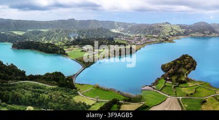 Veduta aerea con drone della Lagoa das Sete Cidades che mostra il ponte iconico che separa i laghi di cratere vulcanico blu turchese e verde smeraldo circondati Foto Stock