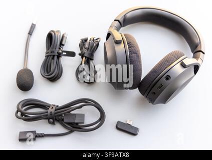Auricolari over-ear neri e accessori sono disposti ordinatamente su una superficie bianca Foto Stock