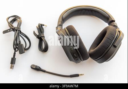 Un auricolare da gioco nero con cavi e microfono poggia su uno sfondo bianco Foto Stock