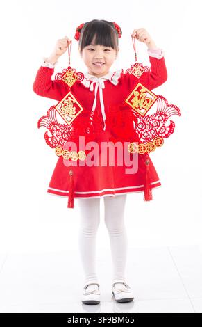 Un ritratto a figura intera di una ragazza asiatica in piedi che tiene due decorazioni rosse per il Capodanno cinese in uno studio bianco. Foto Stock